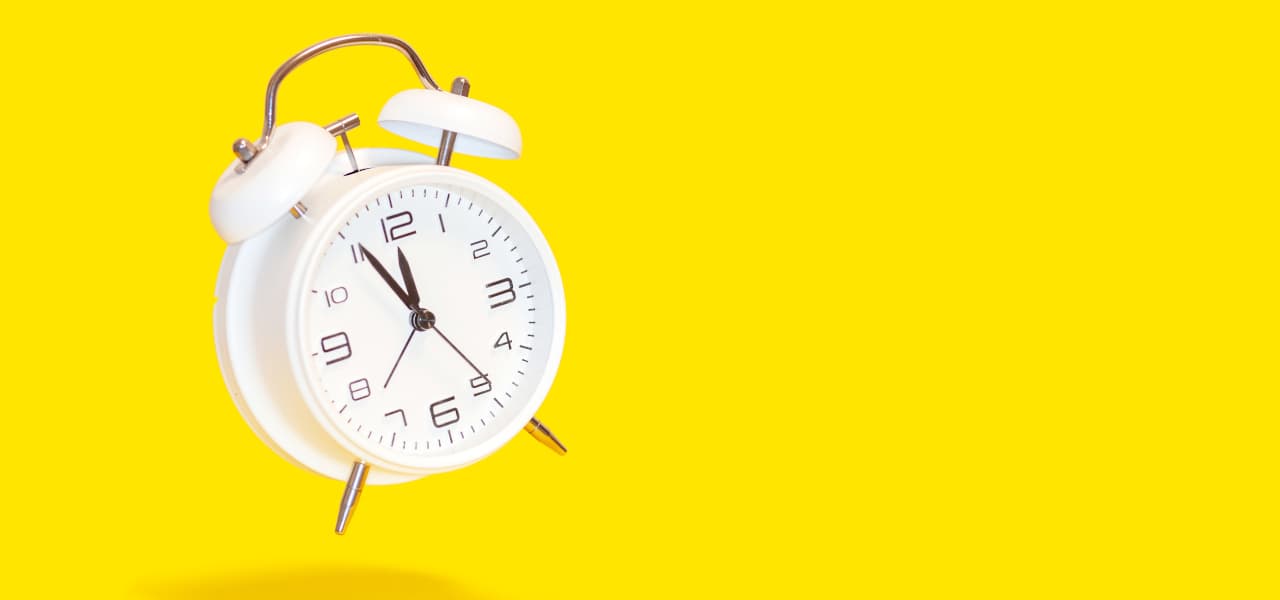 Weißer Wecker vor gelbem Hintergrund zeigt die Uhrzeit 5 vor 12. | Motiv ©ImageSine-stock.adobe.com | © stock.adobe.com, Januar 2025